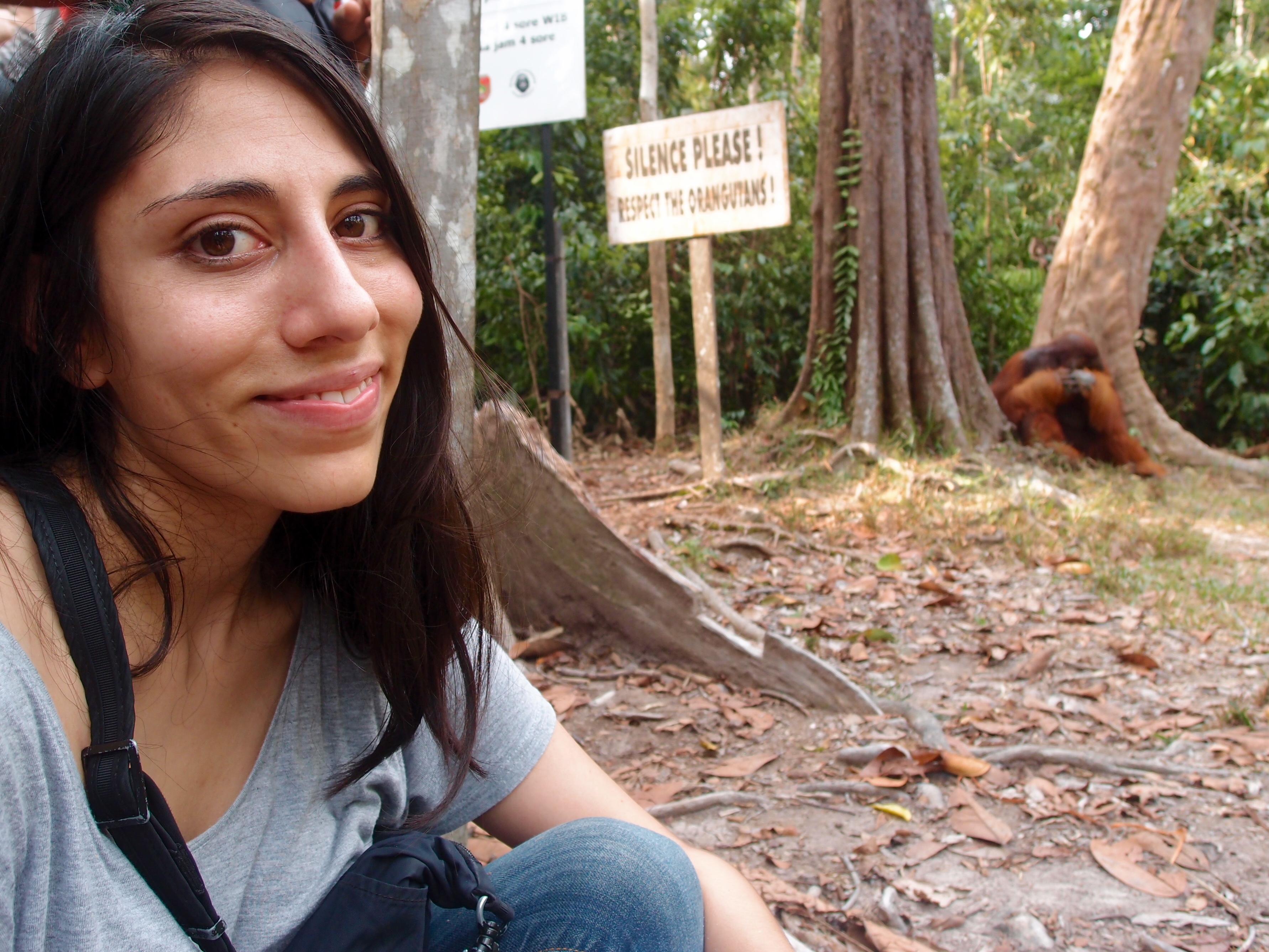Student Outdoors Smiling With Orangutans in the background